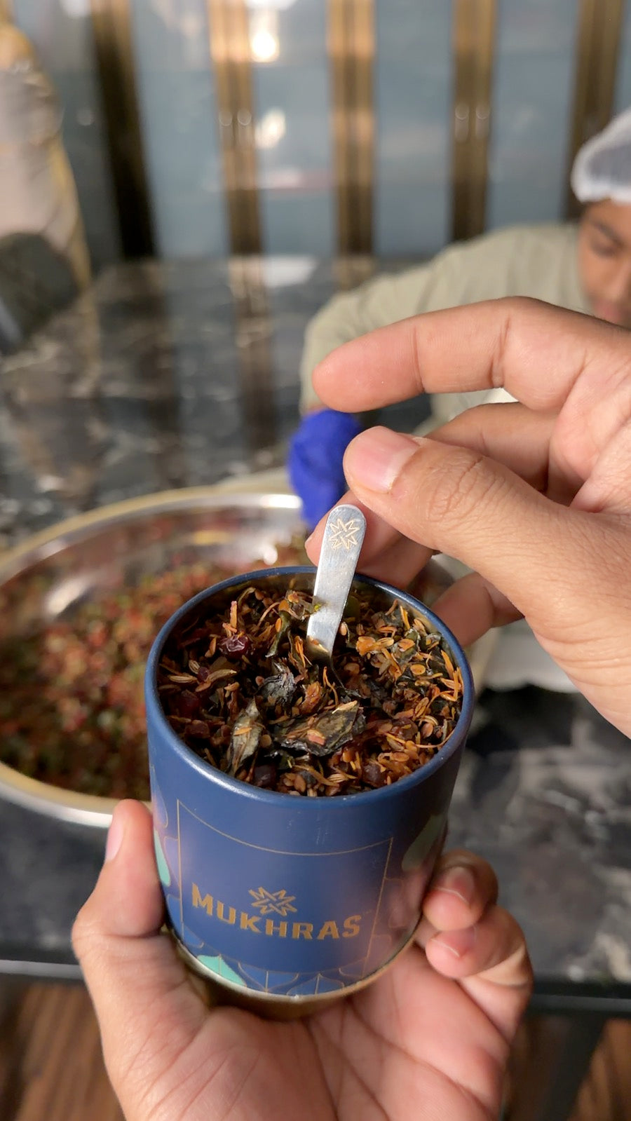 A spoonful of Mukhras going into the jar