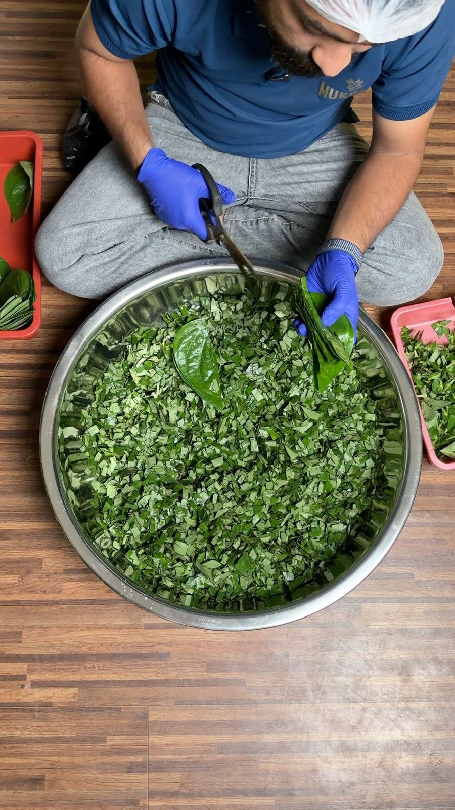 Paan leaves being cut by hand into a steel bowl